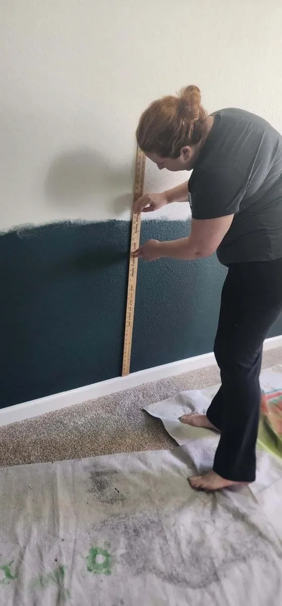 Surface prep technician measuring a feature wall before wallpaper installation