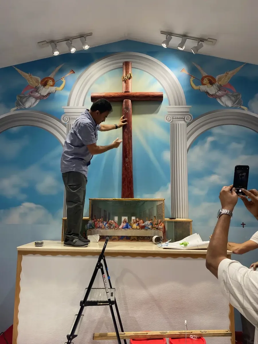 Custom mural wallcovering installer carefully fitting a religious mural panel